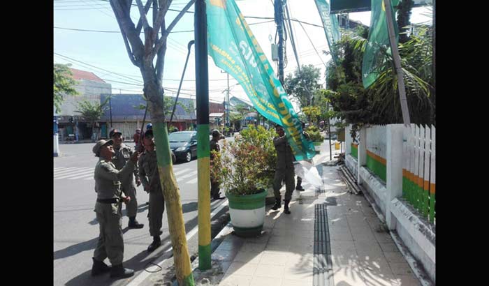 Satpol PP Pamekasan sedang menurunkan paksa salah satu reklame yang tak berizin dan salah penempatan di beberapa titik lokasi di Kabupaten Pamekasan, Selasa (8/5).