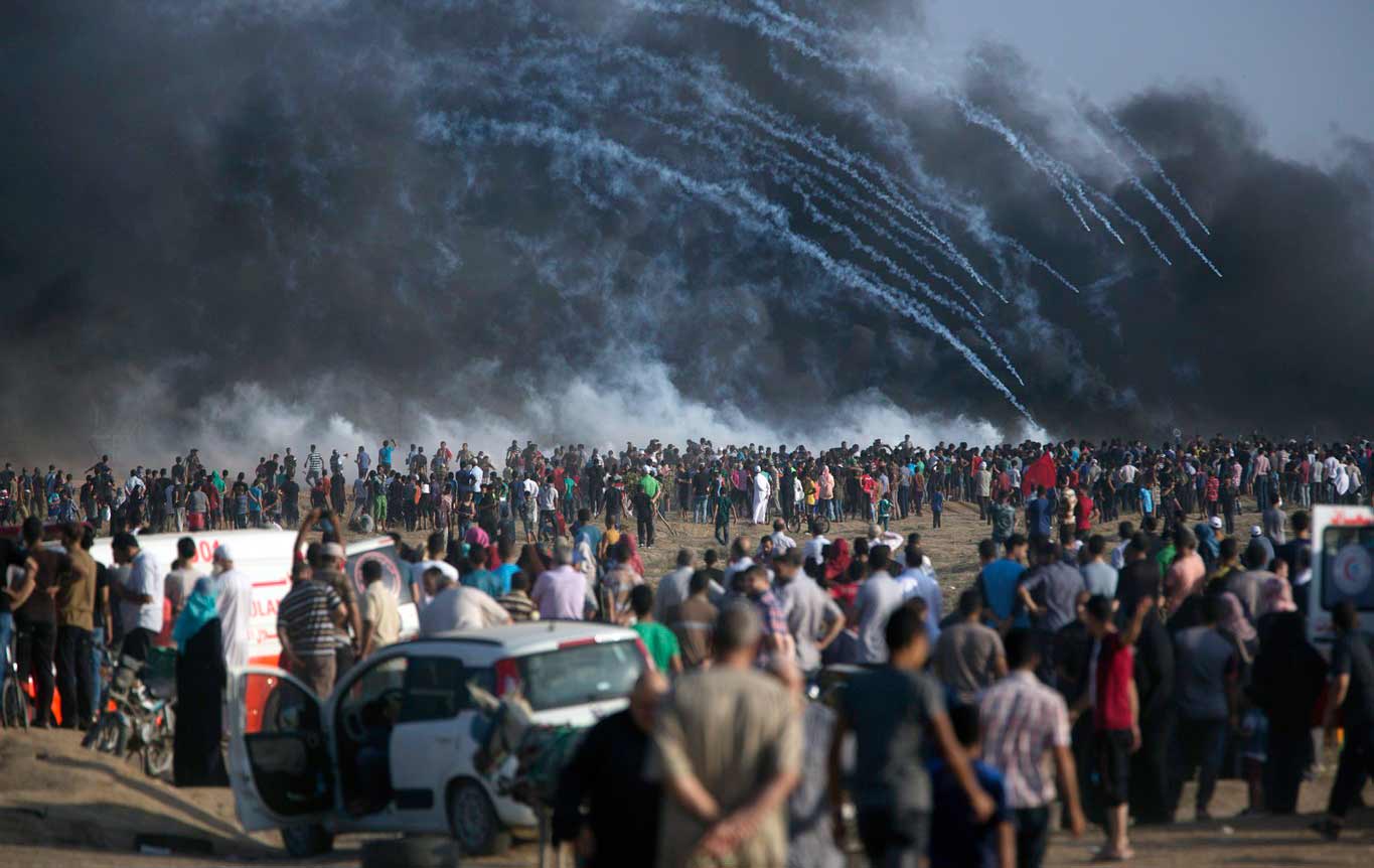 Gas air mata yang ditembakkan oleh pasukan Israel jatuh di atas warga Palestina yang protes di perbatasan Jalur Gaza dengan Israel, Jumat, 13 Juli 2018. Kementerian Kesehatan Gaza mengatakan seorang warga Palestina berusia 15 tahun tewas atas tembakan Israel tersebut. (AP Photo/Khalil Hamra)