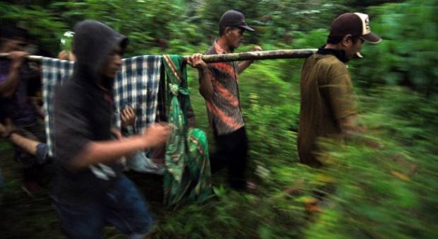 Anggota Polisi membawa anggota kelompok teroris Santoso yang tewas saat baku tembak dengan anggota Brimob dan Densus 88 di Desa Sakina Jaya, Parig, Sulawesi Tengah,3 April 2015. foto: tempo.co