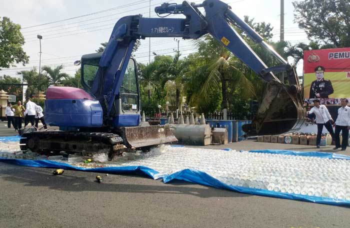 Alat berat backhoe saat memusnahkan ribuan liter miras di halaman Mapolres Tuban.