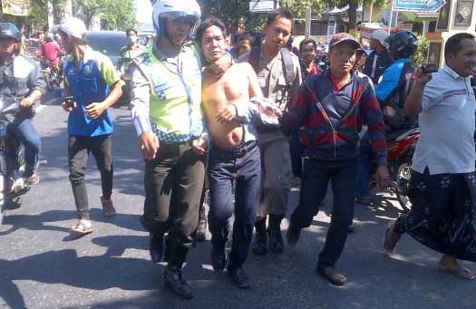 Dimin yang babak belur usai digebuki massa di pasar sedang diselamatkan polisi. (bahri/BANGSAONLINE)