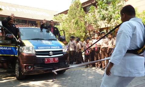 PAKAI GIGI – Nur Muhammad Ramadhan Sunarbiyanto saat menarik mobil berpenumpang lima orang memakai giginya, di halaman SMPN 3 Porong, Jumat (31/10/2014). foto: agus hp/BangsaOnline