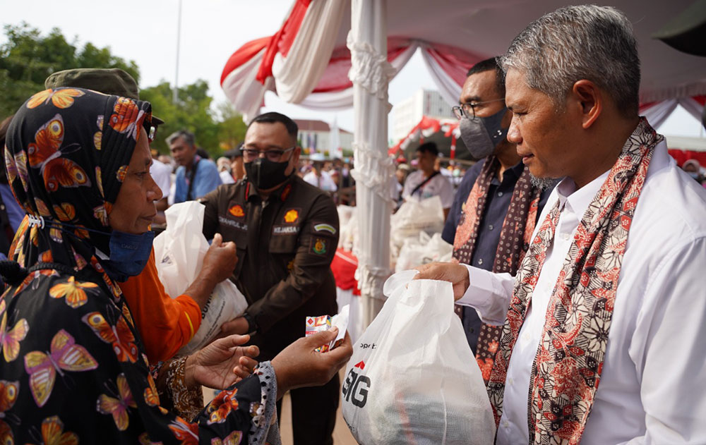 SVP of Supporting SIG Muchamad Supriyadi (kanan) menyerahkan paket sembako murah kepada warga Rembang pada acara Pasar Murah dan Bazar UMKM BUMN di Alun-Alun Rembang, Jawa Tengah. Foto: Ist.