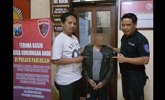 Tersangka saat bersama petugas Satreskrim Polres Pasuruan. 