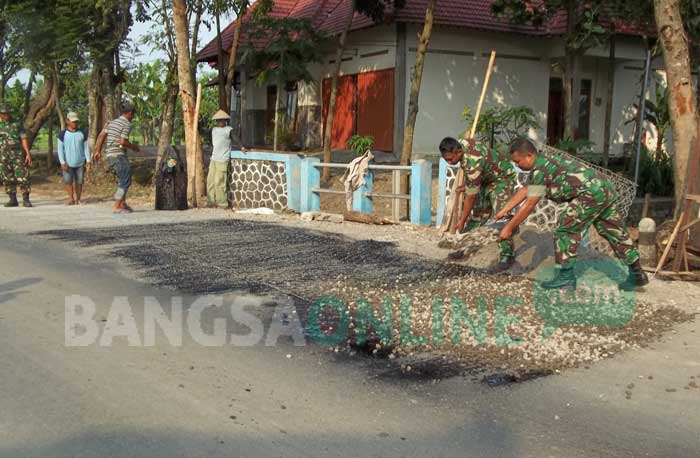 Aparat TNI dari Koramil 0810/13 Lengkong bersama warga memperbaiki jalan berlubang di Dusun Duwel, Desa Jegreg, Kecamatan Lengkong . foto: BAMBANG DJ/ BANGSAONLINE