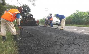 Para pekerja sedang memperbaiki jalan yang berlubang.