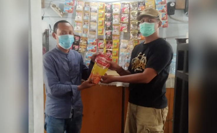 Ketua KWG M. Syuhud Almanfaluty (kiri) memberikan minyak goreng kepada salah satu PKL di sekitar Sekretariat KWG. foto: IST./ BANGSAONLINE