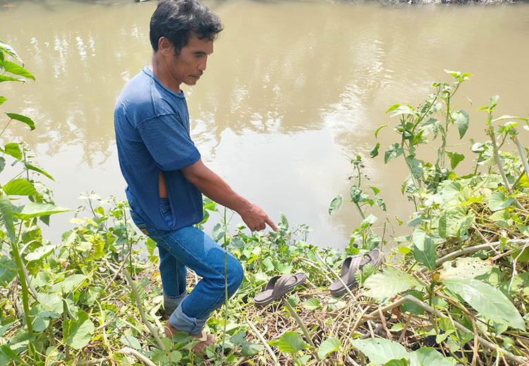 Salah satu warga menujukkan sandal yang diduga milik kakek korban tenggelam di Sungai Kepung, Desa Temu, Prambon, Sidoarjo, Jumat (7/10/2022).