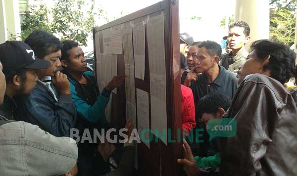 BERDESAKAN: Para pelanggar tilang saat mencocokkan nomer register tilang dengan nomor sidang. foto : nanang ichwan/ BANGSAONLINE