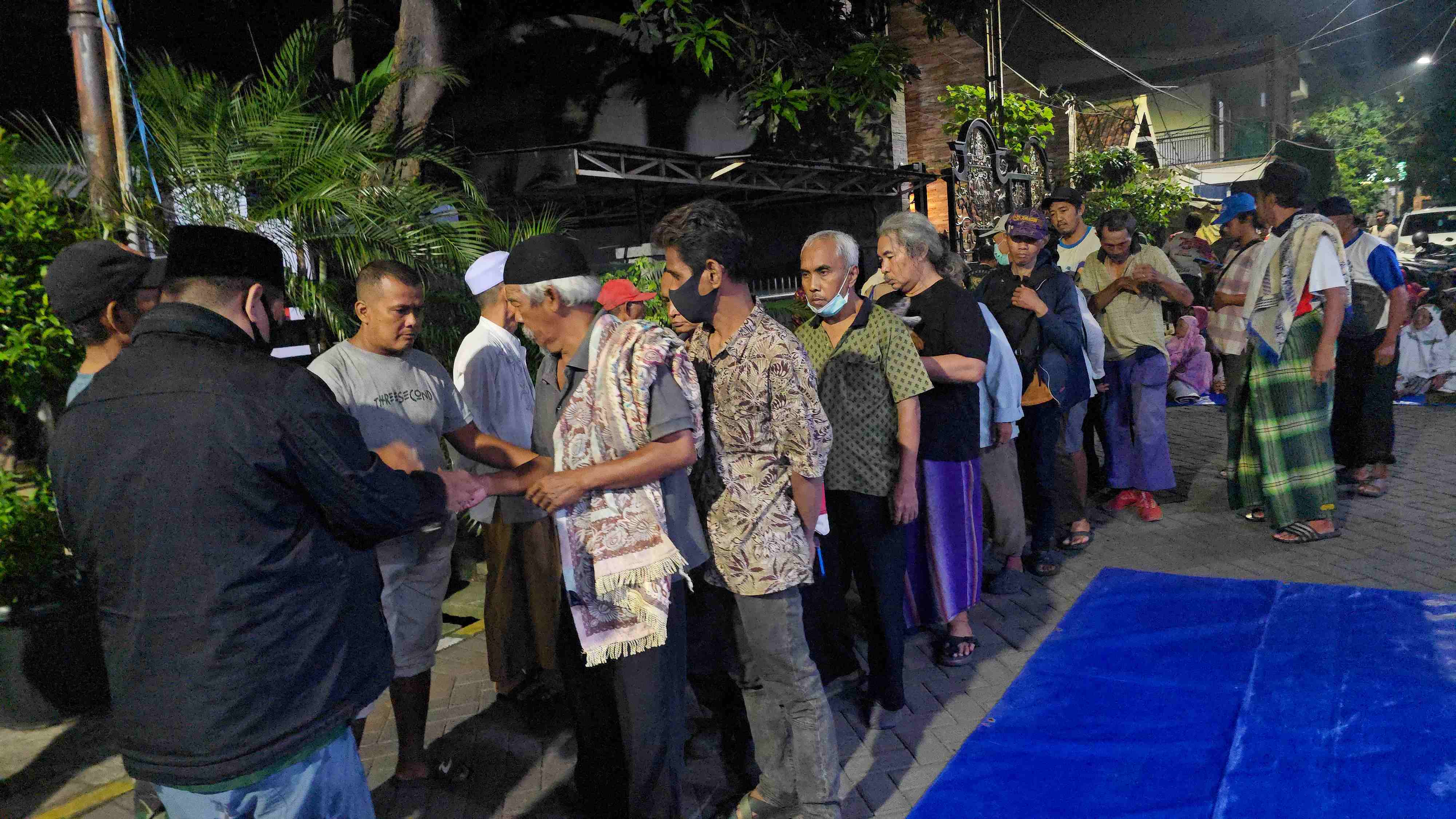 Seorang petugas membagikan sedekah Prof Dr KH Asep Saifuddin Chalim, MA di depan Pondok Pesantren Amanatul Ummah Jalan Siwalankerto Utara Surabaya, Rabu (6/5/2026) malam. Foto: MMA/bangsaonline