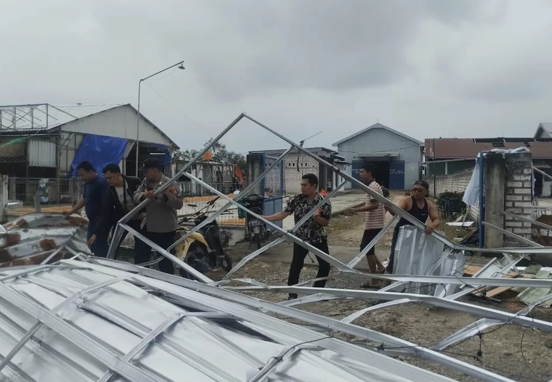 Anggota Polsek Sukodadi bergotong royong bersama warga saat membersihkan puing kanopi yang ambruk diterjang puting beliung