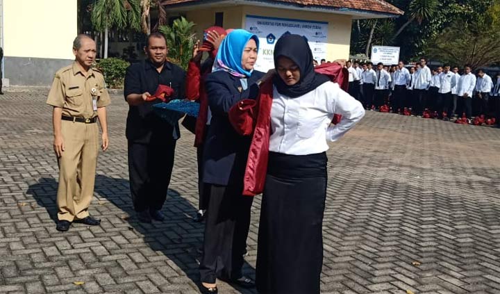 Rektor Unirow Tuban Dr. Supiana Dian Nurtjahyani, M.Kes memakaikan jas almamater pertanda kegiatan KKN dimulai.
