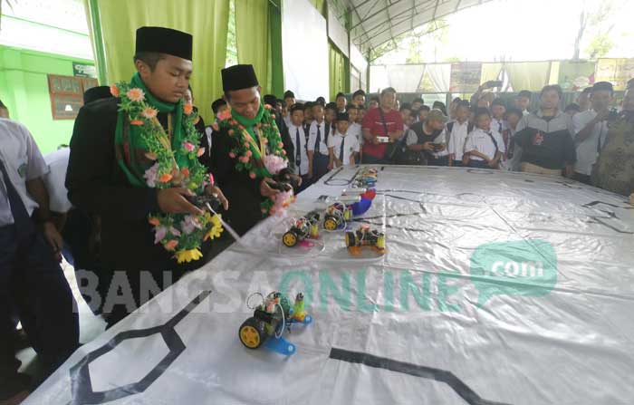Muhammad Reza Hizbulloh dan Yusron Roziqin (berkalung bunga) saat memperaktikan operasional robot yang dia bawa bertarung ke luar negeri. foto: RONY S/ BANGSAONLINE