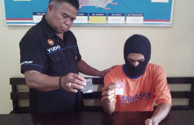 Tersangka didampingi petugas saat menunjukkan barang bukti berupa sabu-sabu. (foto: dendi martoni/BANGSAONLINE)
