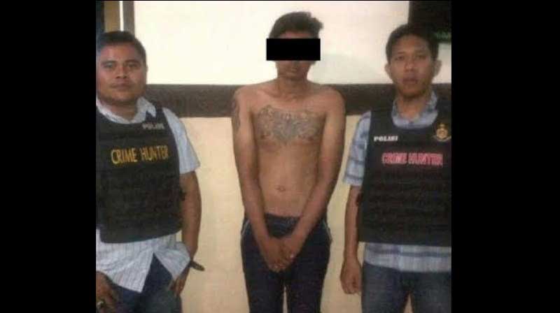 Salah satu tersangka diapit petugas di Mapolsek Sawahan. foto: ekoyono/ BANGSAONLINE