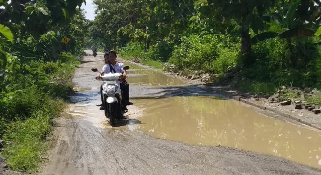 Pengendara motor harus zig-zag untuk menghindari kubangan yang cukup dalam dan licin.