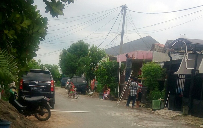  Warga bekerja bakti menutupi tiang lampu yang terbuat dari pipa besi dengan pipa paralon.
