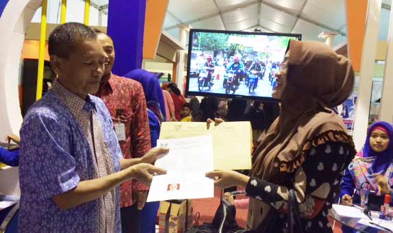 Kepala BPM Kota Kediri Triyono Kutut saat menyerahkan SIUP dan TDP kepada salah seorang warga setelah mengurus di stand BPM. foto: arif kurniawan/ BANGSAONLINE
