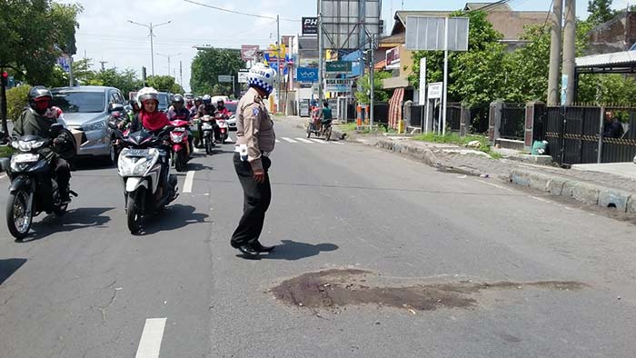 Petugas usai menutupi jalan bekas darah korban dengan pasir.