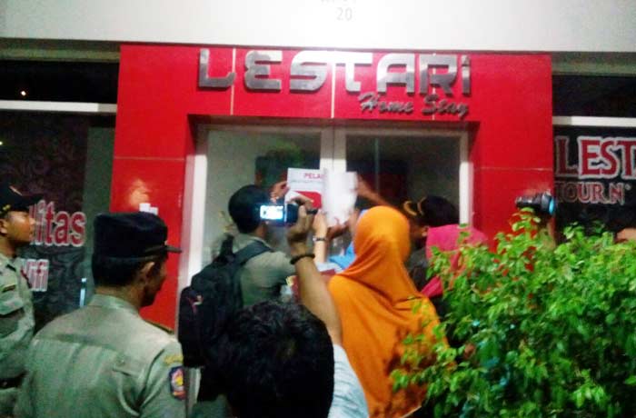 Petugas Satpol PP saat menyegel Homestay Lestari di Jalan Dr. Wahidin SH Kebomas. foto: SYUHUD/ BANGSAONLINE