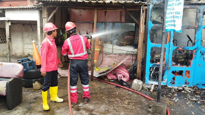 Tim Damkar Pemkab Gresik saat memadamkan toko sembako dan warkop yang terbakar. Foto: SYUHUD/ BANGSAONLINE.com