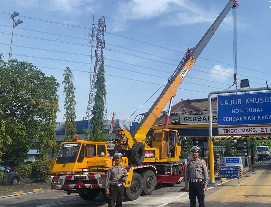 Petugas saat melakukan evakuasi material pintu tol yang rusak