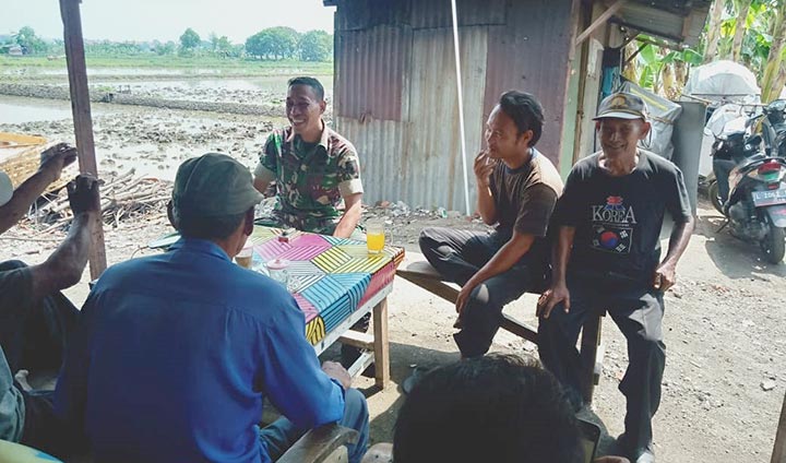 Babinsa Koramil Kenjeran, Serda Budi Hermanto berbincang dengan warga Jalan Memet, Kenjeran.