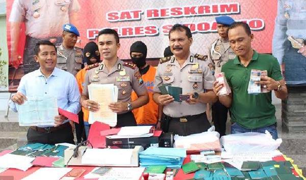 Kapolres Sidoarjo, AKBP M Anwar Nasir menujukkan barang bukti yang dipalsukan oleh sindikat pengiriman TKI ilegal dalam publik ekspos di Mapolres Sidoarjo,kemarin. foto: catur andy erlambang/ BANGSAONLINE
