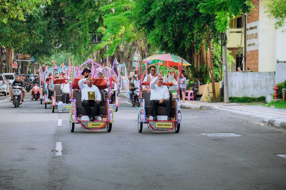 Bupati Gresik Fandi Akhmad Yani dan Wabup Asluchul Alif dengan naik becak listrik  kirab Adipura. foto: ist.