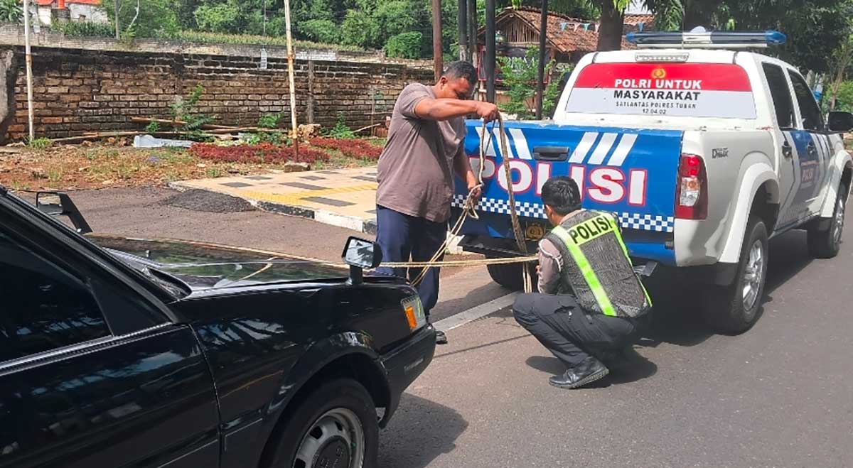 Petugas dari Satantas Polres Tuban saat membantu pengendara mobil yang mogok.