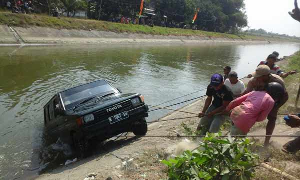 RAMAI-RAMAI. Warga saat membantu mengevakuasi mobil yang tercebur di sungai. (foto: dendi martoni/BANGSAONLINE)