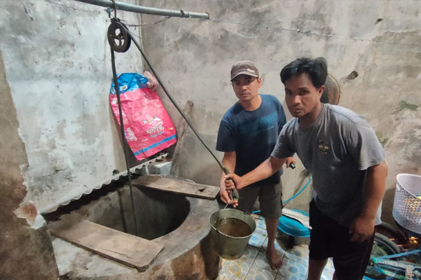 Ketua RT 5 RW 2 Kelurahan Tempurejo (kiri) saat menunjukkan air sumur yang diduga tercemar. 