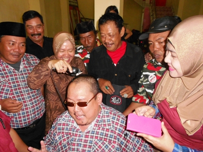 Wali Kota Surabaya Tri Rismaharini mencukur rambut Ketua Umum Gerakan Rakyat Jawa Timur (GRJ), Mat Mochtar, tokoh Madura yang menjadi relawan Jokowi - JK. Foto:diday rosady/BANGSAONLINE