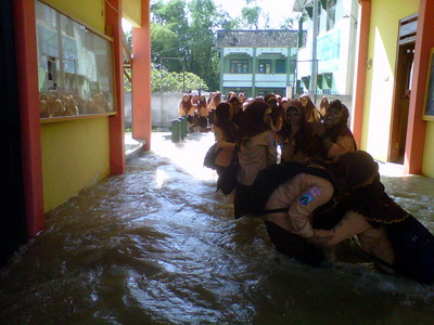 ?Siswi SMA Attanwir Talun, Sumberjo harus melawan derasnya air saat pulang menuju kamar. Foto:eky nur hadi/bangsaonline.