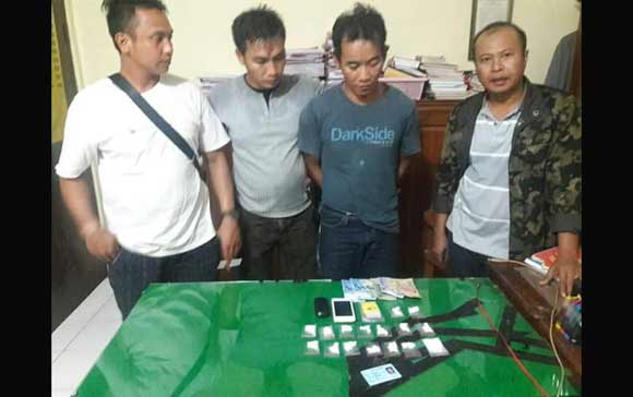 Sugiyono diapit petugas Reskrim bersama barang buktinya.
