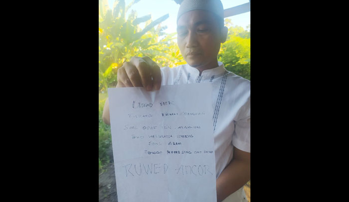 Ustaz Ansori sedang menunjukkan surat berisi penghinaan yang ditujukan kepadanya.
