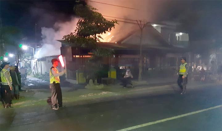 Petugas mengamankan lokasi di sekitar warung sate milik Turmudi yang terbakar.