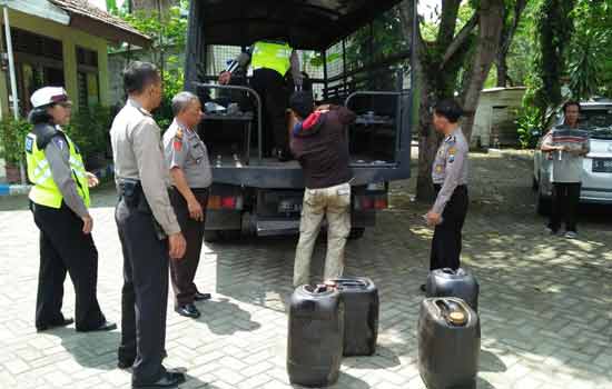 Polisi saat menurunkan barang bukti tujuh jerigen yang berisi minyak olahan dari truk untuk diamankan di Mapolres. foto: EKY NURHADI/ BANGSAONLINE