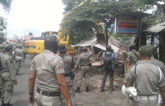 Petugas menggunakan alat berat saat melakukan pembongkaran. foto: MURSIDI/ BANGSAONLINE