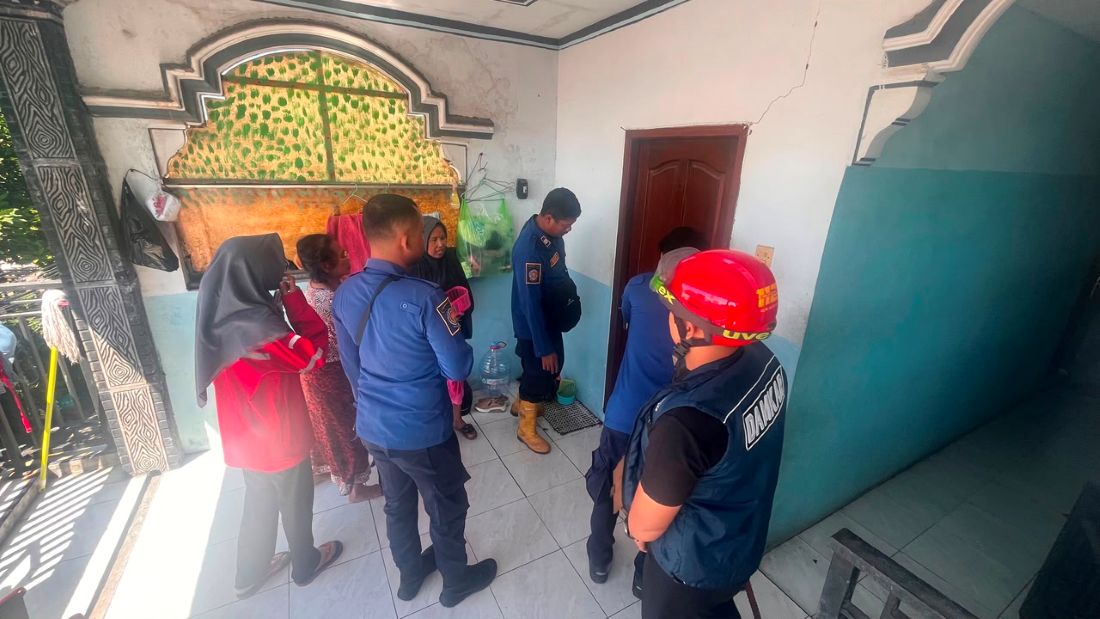Anggota Damkar Gresik saat akan membuka paksa kamar kos yang terkunci dari dalam