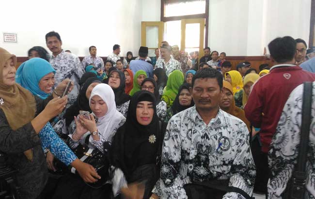 Terdakwa Muhammad Samhudi (tengah) diapit dan diajak foto oleh para guru PGRI Sidoarjo, saat hendak duduk di kursi pesakitan PN Sidoarjo untuk menjalani persidangan. foto: NANANG I/ BANGSAONLINE
