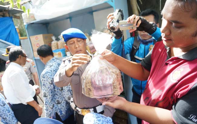 Petugas saat menunjukkan salah satu makanan yang tak layak konsumsi karena telah kadaluarsa. foto: RONY S/ BANGSAONLINE