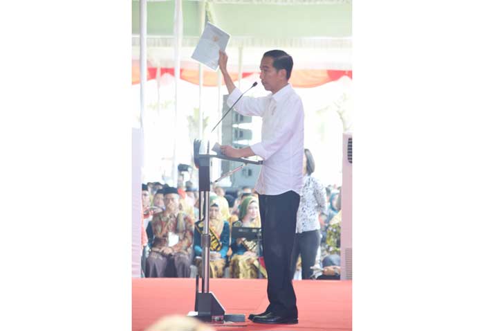 Presiden Jokowi saat memperlihatkan sertifikat tanah di depan masyarakat yang akan menerimanya.