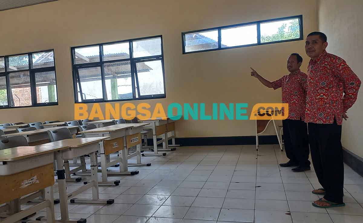 Bagian Sarana dan Prasarana SMPN 1 Kutorejo, Moh Antoni, didampingi Humas SMPN 1 Kutorejo saat memperlihatkan ruang kelas yang selesai direhab. Foto: ROCHMAT SAIFUL ARIS/BANGSAONLINE