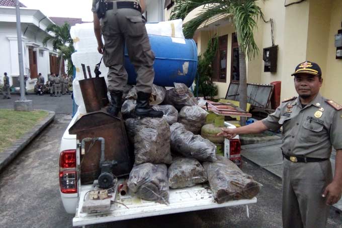 Petugas mengamankan alat-alat yang digunakan untuk memproduksi arak. foto: SUWANDI/ BANGSAONLINE