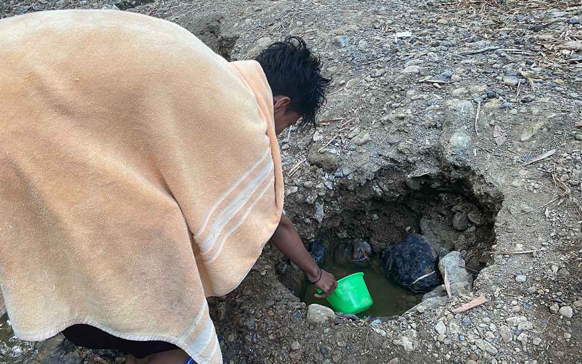 Salah satu warga dari Kecamatan Robatal, Sampang, saat menampung air keruh di pinggir sungai. Foto: Ist