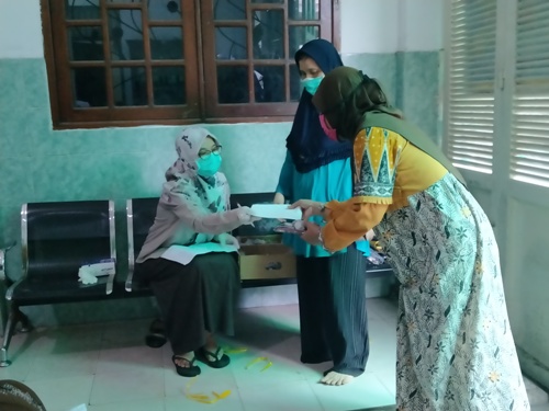 Ning Zahroh, putri Nyai Hj. Alif Fadlilah saat membagikan uang, kurma dan sewek kepada para janda di kediamannya Jalan Siwalankerto Utara, Jumat (22/5/2020). FOTO: MMA/ bangsaonline.com 
