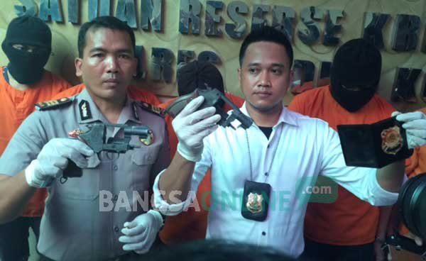 Kasat Reskrim bersama Kasubag Humas saat menujukkan senjata api yang digunakan para pelaku untuk menakut-nakuti korban. foto: arif kurniawan/ BANGSAONLINE