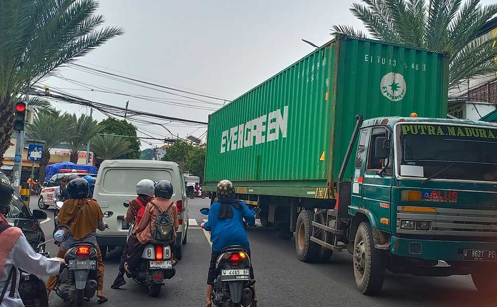 Truk tronton berhenti di tengah jalan usai nyangkut kabel seluler yang menggelantung di perempatan Jalan Giri, Kebomas, Gresik. Foto: SYUHUD/ BANGSAONLINE