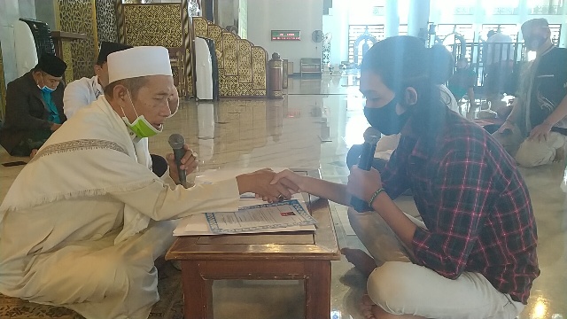 Imam Masjid Nasional Al-Akbar KH Abdul Hamid Abdullah menjabat tangan Bryan Febriyanto saat menuntun ikrar baca dua kalimat syahadat di  Masjid Nasional Al-Akbar, Surabaya, Jumat (10/7/2020). foto: MMA/ bangsaonline.com